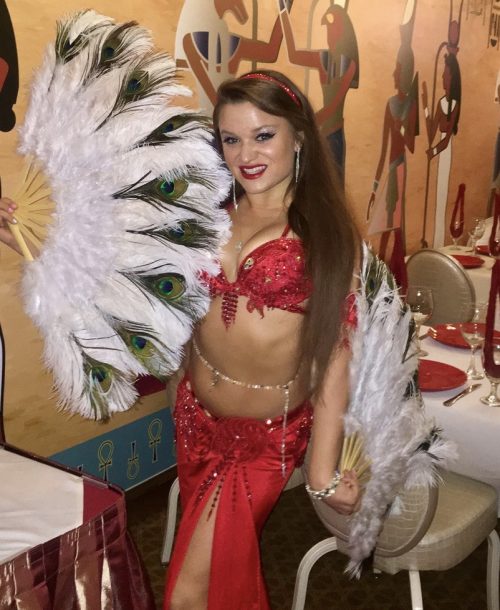 Bellydancer posing with feathered fans and a red outfit, wearing a long drop chain bellybelt.