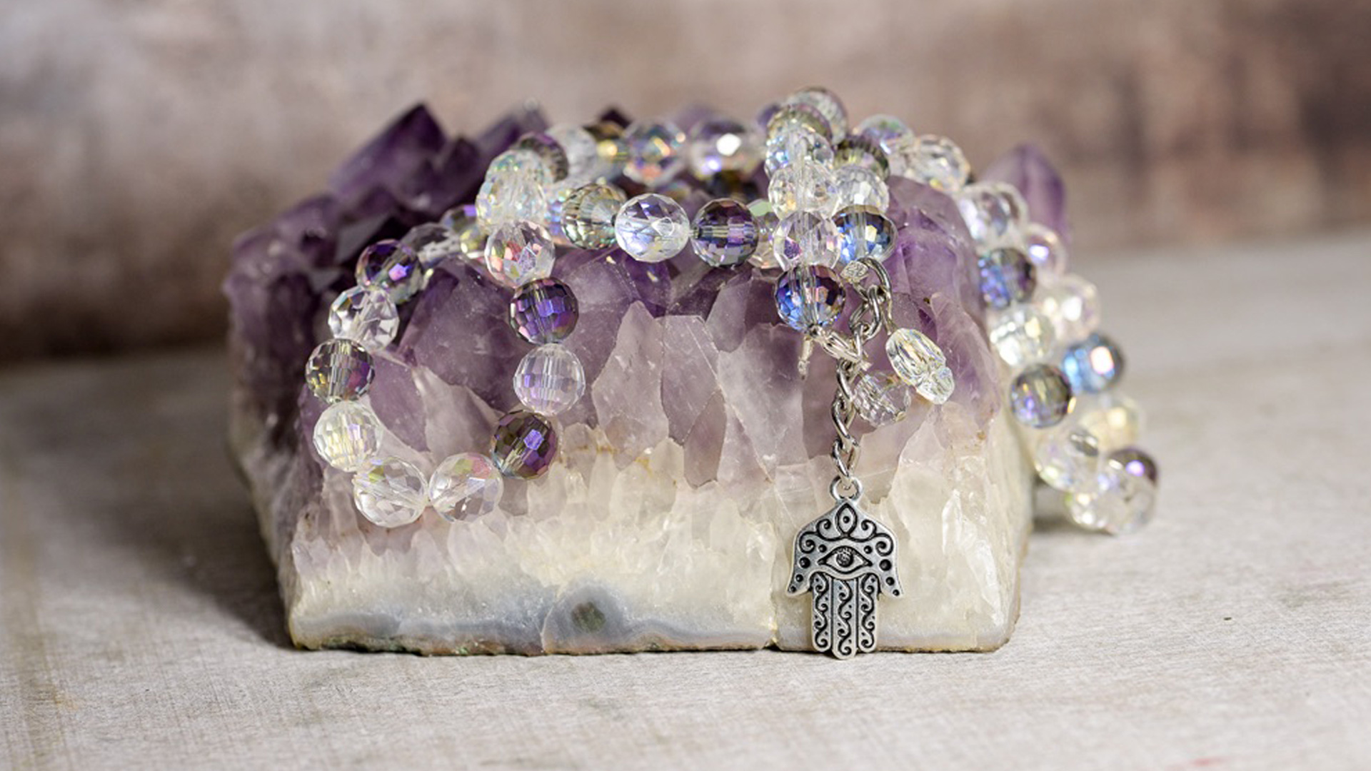 Khamsa BellyBelt with light purple and clear beads and a silver Khamsa pendent on a purple gemstone rock.