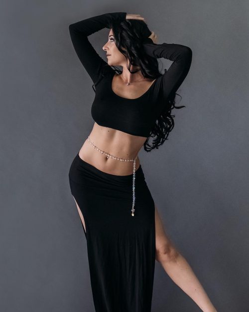 Dancer posing in a black outfit wearing a clear and light beaded bellybelt.
