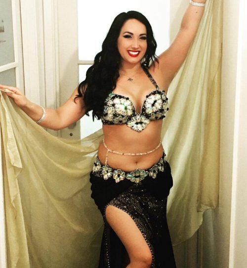 Bellydancer in a dark outfit with golden wrap wearing a gold and clear beaded bellybelt.
